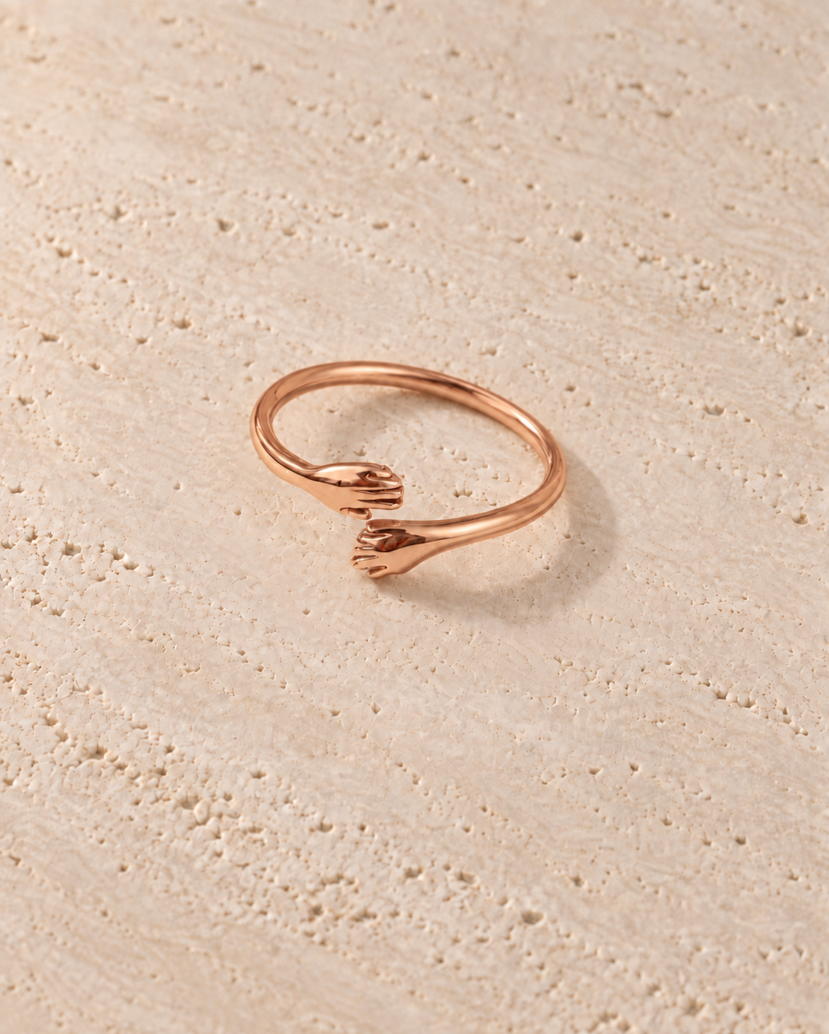 Abbraccio Hug Ring in goudkleur op warm travertin