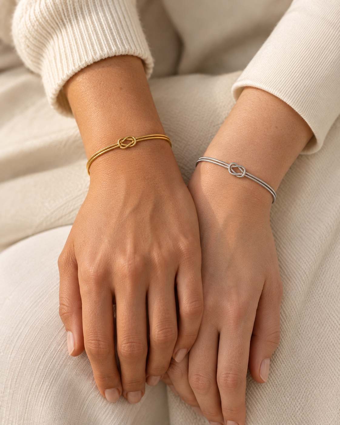 Twee polsen met de Legame Knot Bracelet in goudkleur en zilverkleur